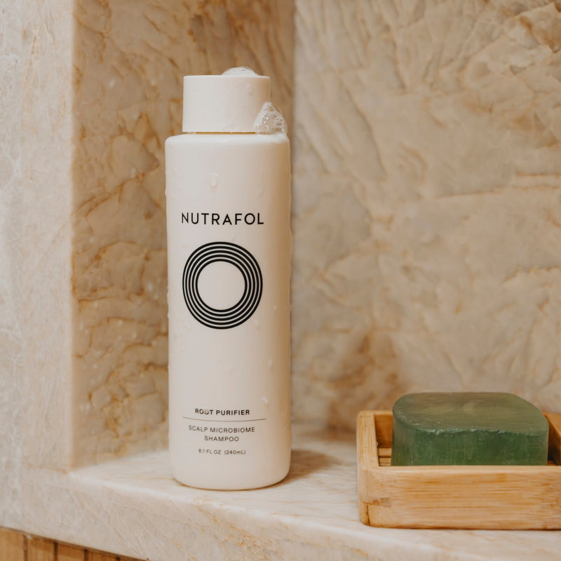 Nutrafol Root Purifier Shampoo displayed in a stone shower niche
