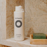 Nutrafol Root Purifier Shampoo displayed in a stone shower niche