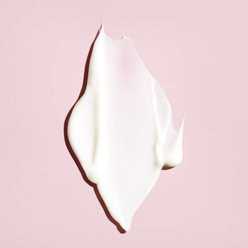 Creamy white texture of Oribe Conditioner for Beautiful Color on a blush pink background