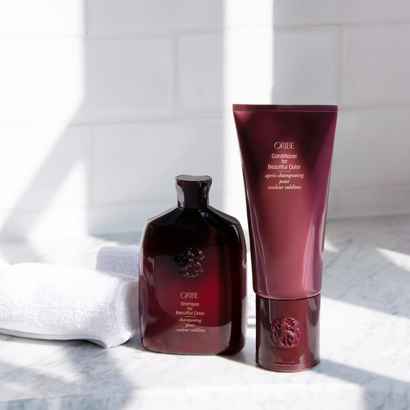 Oribe Shampoo and Conditioner for Beautiful Color displayed with white towels in a bright shower