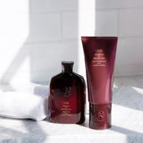Oribe Shampoo and Conditioner for Beautiful Color displayed with white towels in a bright shower