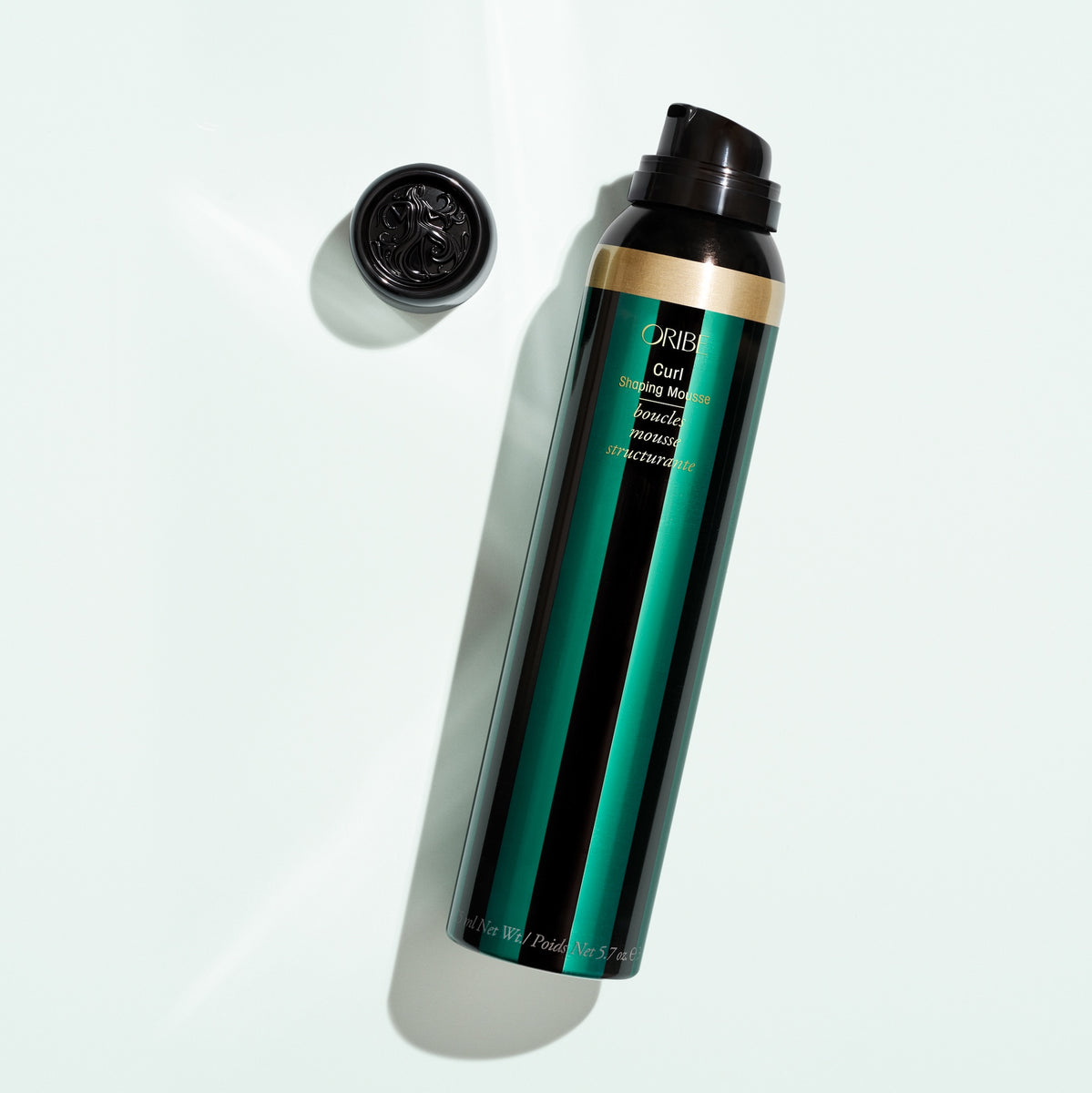 Oribe Curl Shaping Mousse 5.7 oz bottle shown uncapped with the dispensing nozzle on a pale studio background