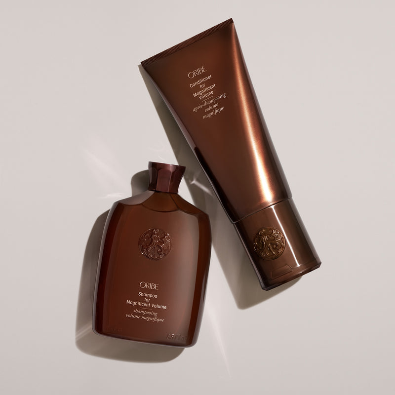 Oribe Shampoo and Conditioner for Magnificent Volume styled on a neutral background