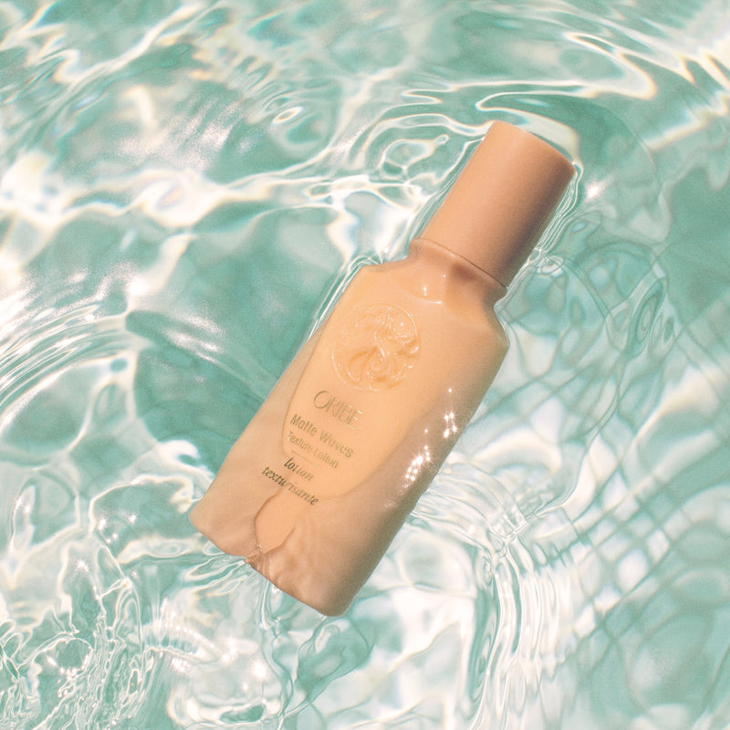 Oribe Matte Waves Texture Lotion bottle floating in turquoise water