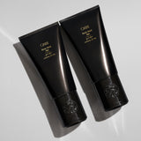 Two Oribe Rock Hard Gel black tubes arranged diagonally on a light gray studio surface with sharp directional shadows