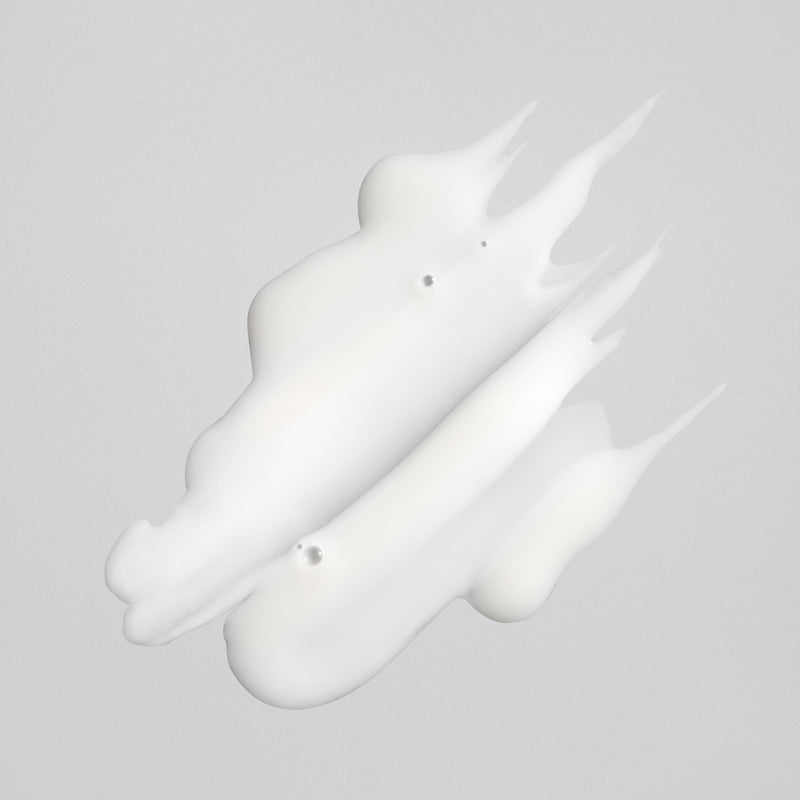 Creamy white texture of Oribe Rock Hard Gel spread into three sculpted strokes with pointed peaks on a pale gray surface