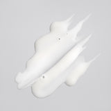 Creamy white texture of Oribe Rock Hard Gel spread into three sculpted strokes with pointed peaks on a pale gray surface