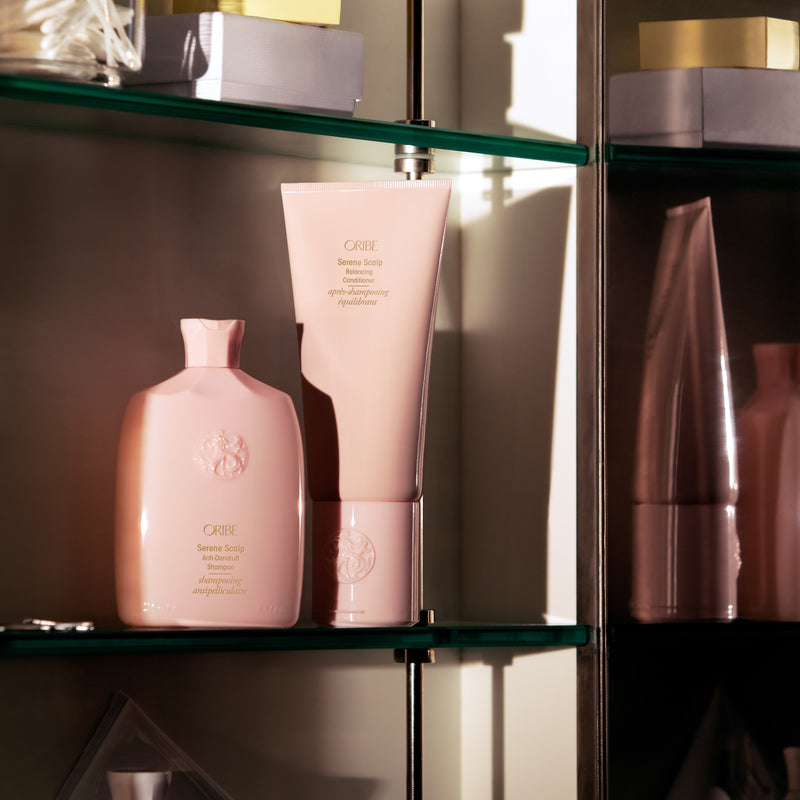 Oribe Serene Scalp Anti-Dandruff Shampoo and Balancing Conditioner displayed on glass shelves