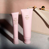 Oribe Serene Scalp Soothing Leave-On Treatment displayed beside Serene Scalp Exfoliating Scrub on a soft pink surface