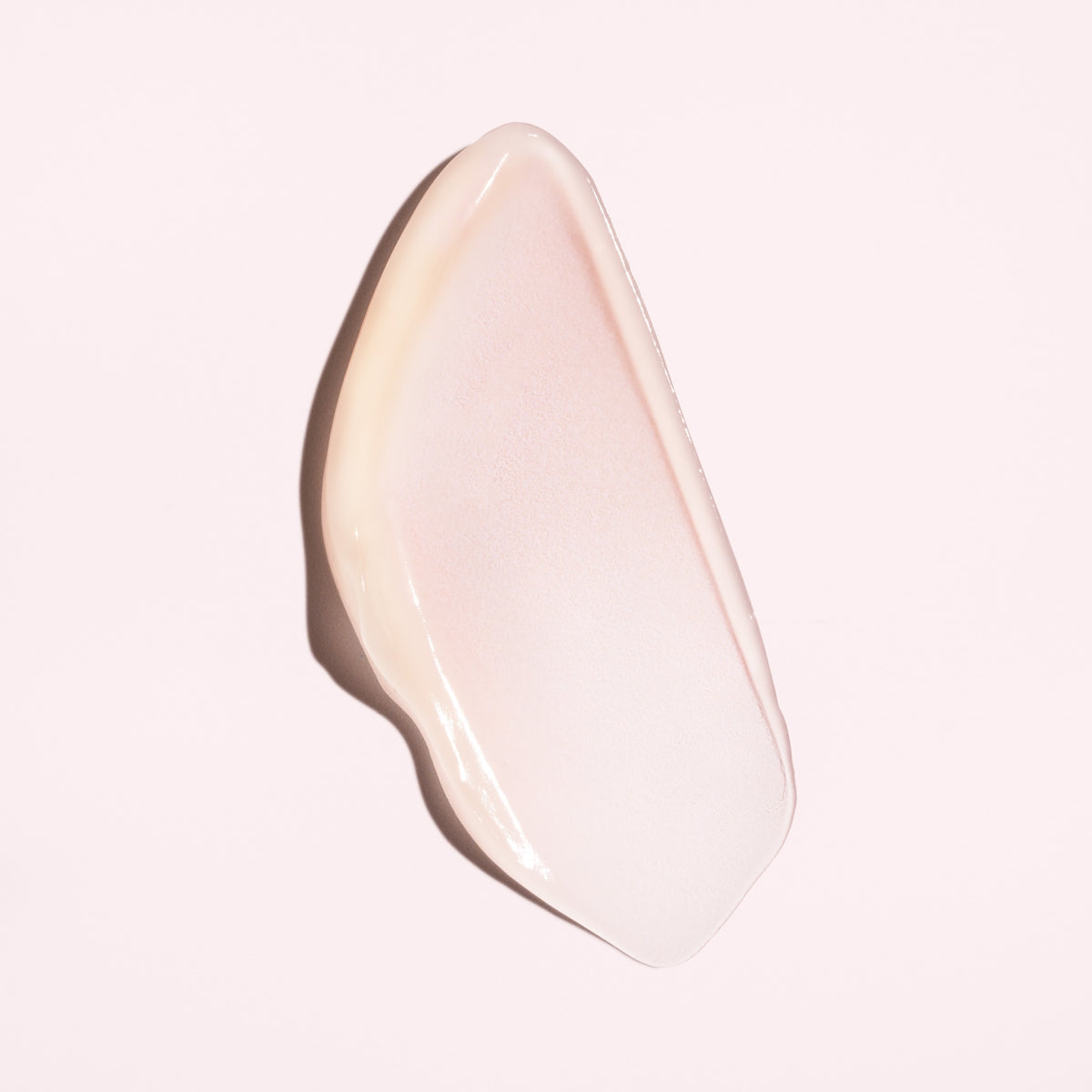 Silky pale pink cream texture of Oribe Serene Scalp Soothing Leave-On Treatment spread into a smooth sweep on a blush background