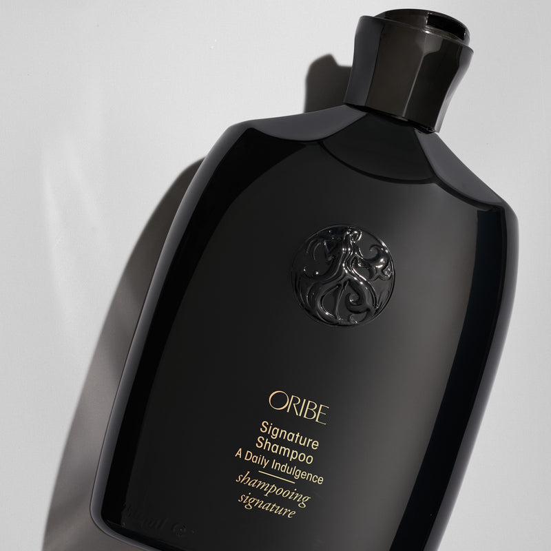 Close-up of Oribe Signature Shampoo bottle on a pale gray background