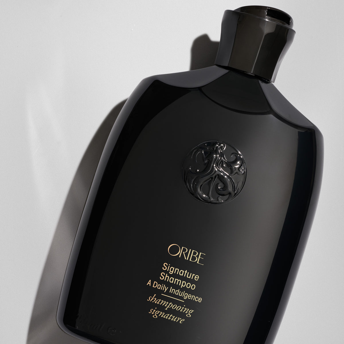 Close-up of Oribe Signature Shampoo bottle on a pale gray background