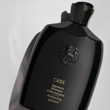 Close-up of Oribe Signature Shampoo bottle on a pale gray background