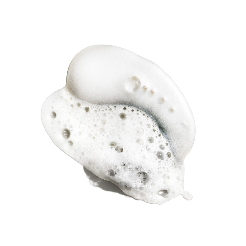 Pearlescent white lather from Oribe Silverati Shampoo with fine foam, translucent bubbles and a soft silvery sheen on white
