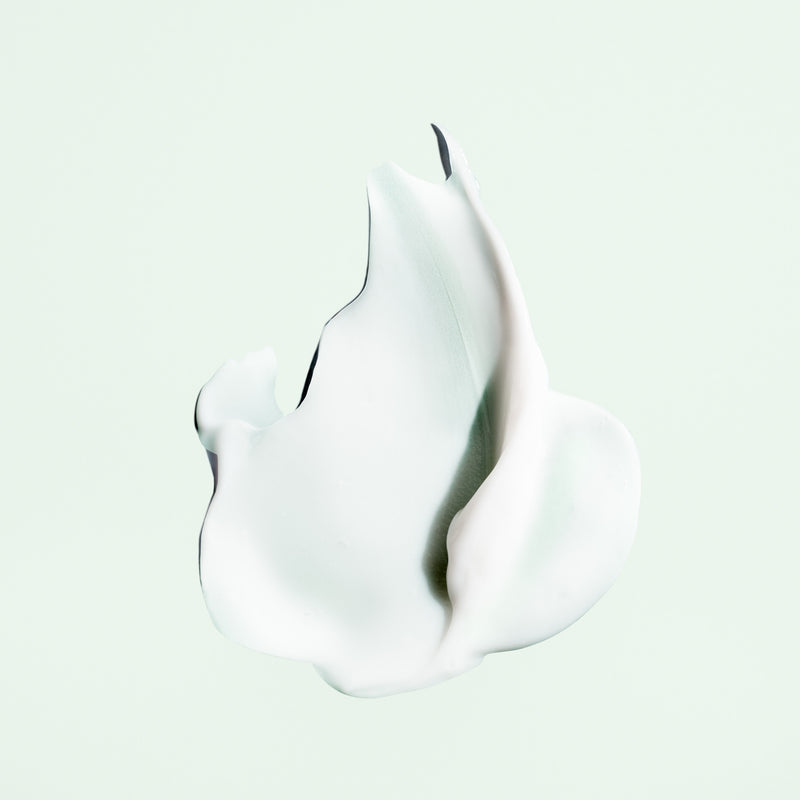 Cream texture of Oribe Styling Butter Curl Enhancing Crème on a pale green background