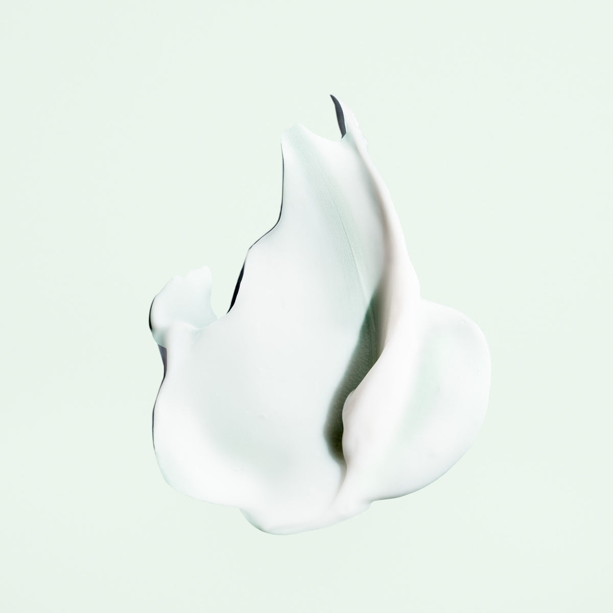 Cream texture of Oribe Styling Butter Curl Enhancing Crème on a pale green background