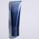 Oribe Supershine Light Moisturizing Cream tube on a pale gray background