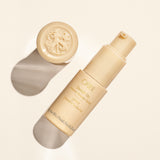 Oribe Swept Up Volume Powder Spray 0.21 oz shown uncapped with its pump dispenser and embossed cap on a warm ivory studio surface with crisp directional shadows