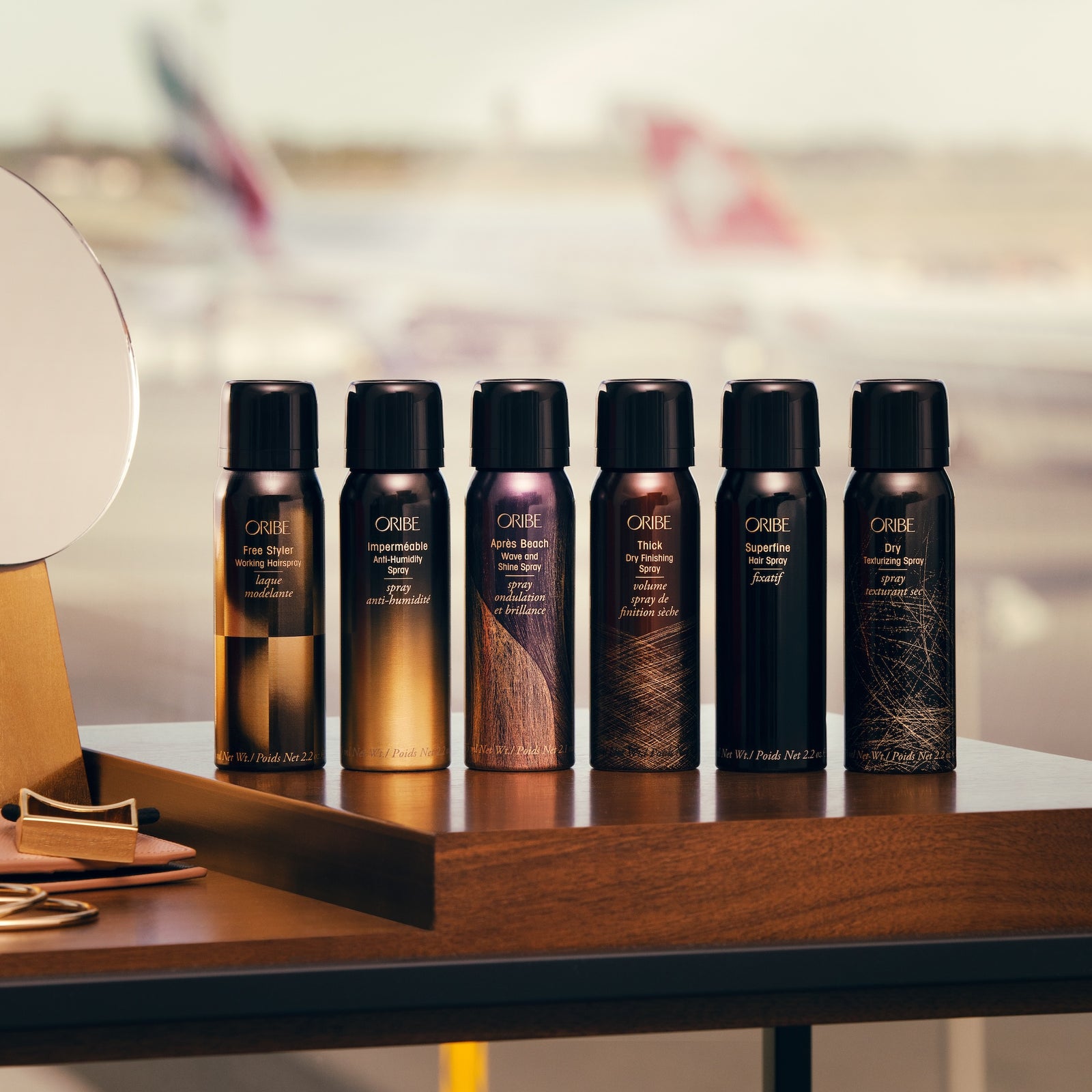 Oribe travel size styling sprays arranged on a salon vanity